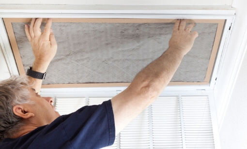 A technician changing an air filter in the ceiling.